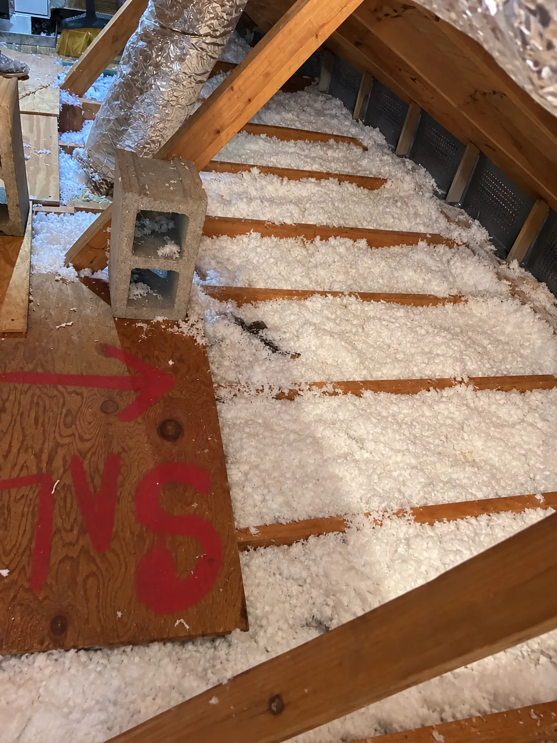 Attic detail with insulation, framing and a marked board